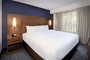 Ein Hotelzimmer mit einem großen Bett, zwei Nachttischen mit Lampen, einem Telefon und einem Fenster mit Vorhängen.
