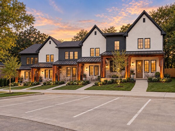 A multi-story residential building with a symmetrical facade, large windows, and a well-maintained lawn.
