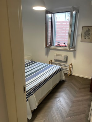 A bedroom with a bed, a window with blinds, a radiator, and a door. - A 13-minute bike ride from downtown Forte dei Marmi: apartment with a terrace (Ripa- Pozzi-Ponterosso)