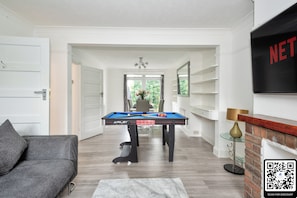 Een biljarttafel in een goed verlichte kamer met een open haard, een bank en een QR-code voor kortingen.