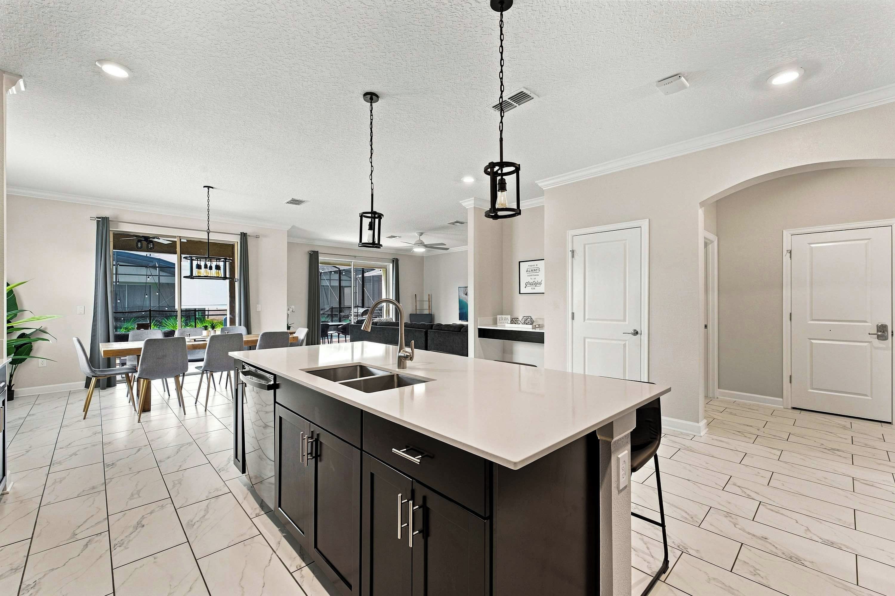 A modern kitchen with a central island, dark cabinetry, and pendant lighting.
