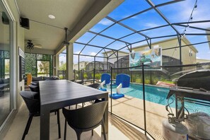 Ein überdachter Patio-Bereich mit Pool, Gartenmöbeln und Grill.