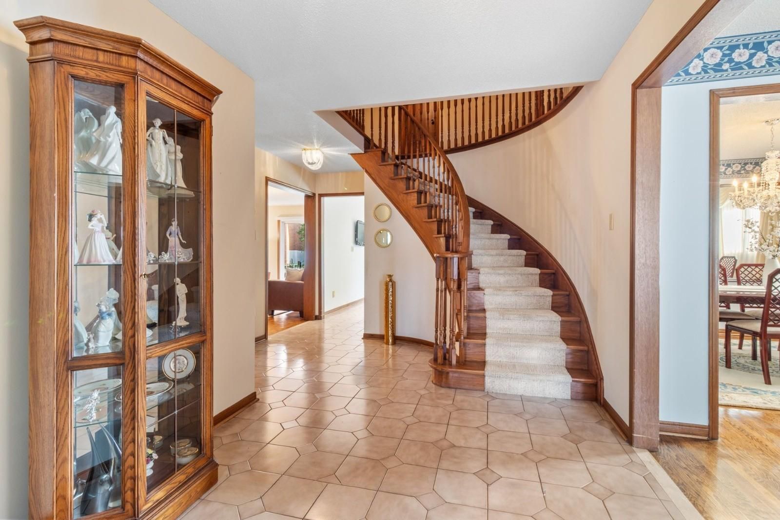 Grand entry foyer with elegant curved staircase and warm classic finishes