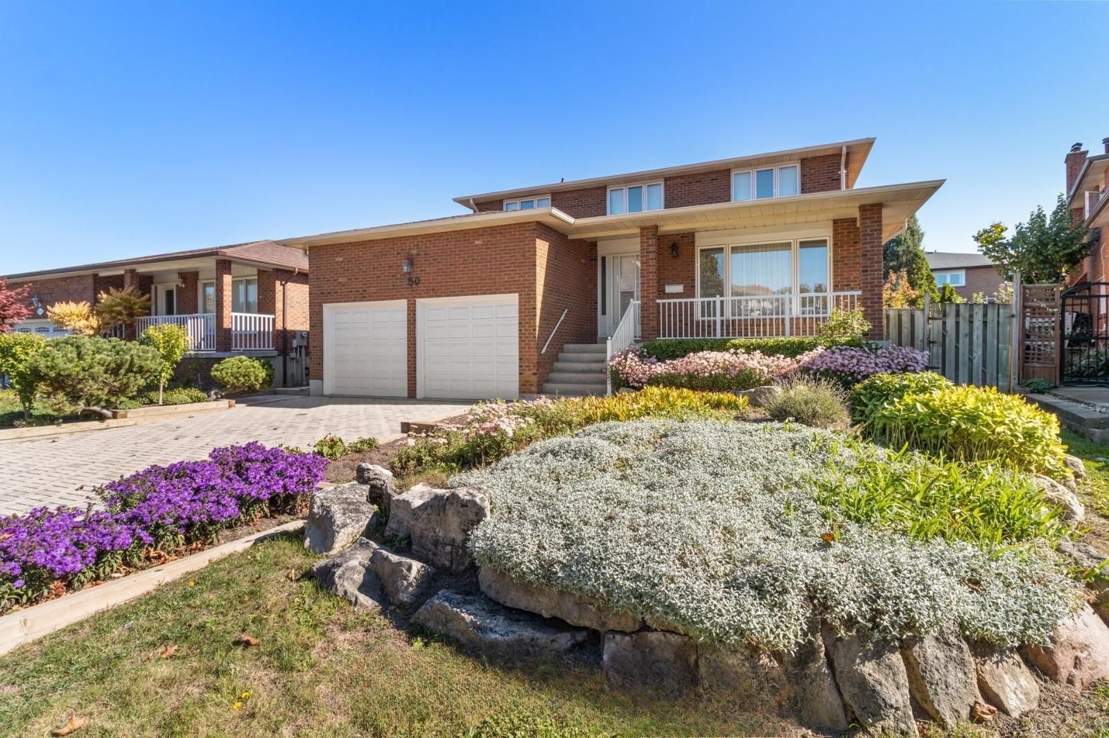A two-story residential building with a brick facade, a front porch, and a driveway.