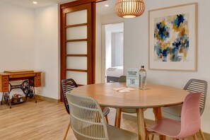A dining area with a round table, chairs, a sewing machine, and a framed abstract painting. - w* | Amazing 2BR in Zona T (Bogotá)