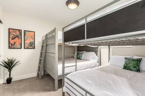 Ein Schlafraum mit Etagenbett, einer Leiter, zwei gerahmten Bildern an der Wand und einer Topfpflanze.