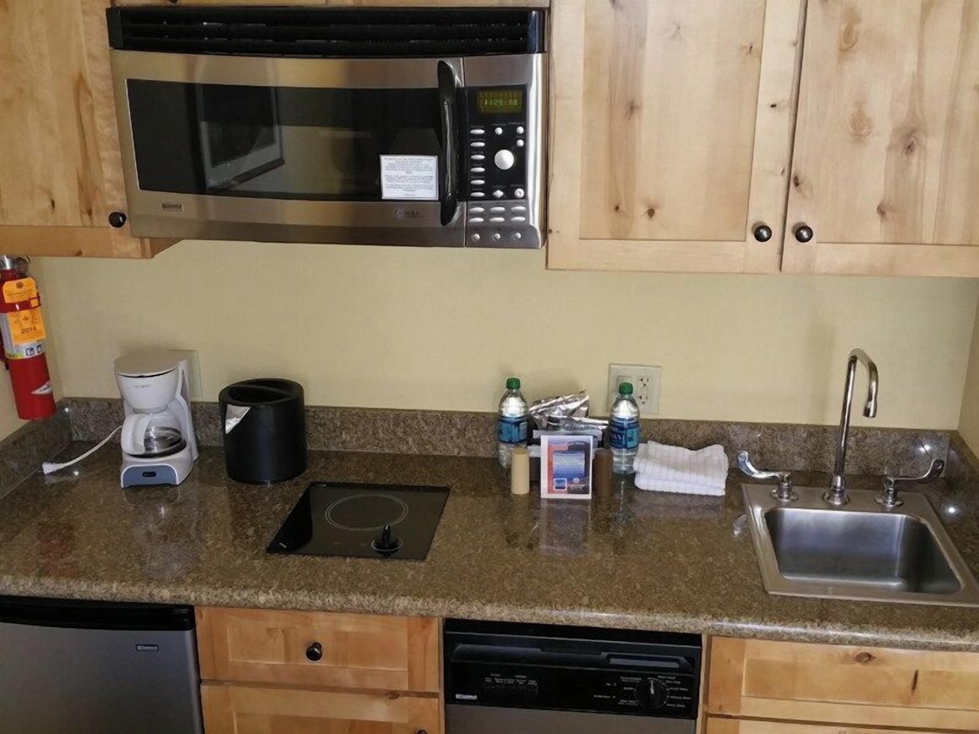 A kitchen with a microwave, coffee maker, sink, and dishwasher.