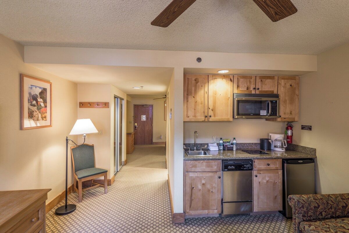 A compact kitchen with wooden cabinets, a microwave, and a dishwasher.
