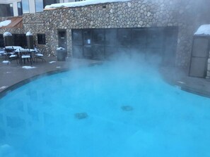 A stone building with a pool emitting steam, surrounded by outdoor seating. - NEW LISTING - 279/281-2 Room Suite @Base area Mt. CB ski area (Crested Butte)