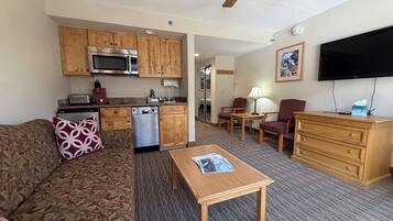 A compact living space with a kitchenette, a sofa, a coffee table, a TV, and a dining area.