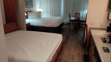 A hotel room with two beds, a dining area, and a kitchenette.