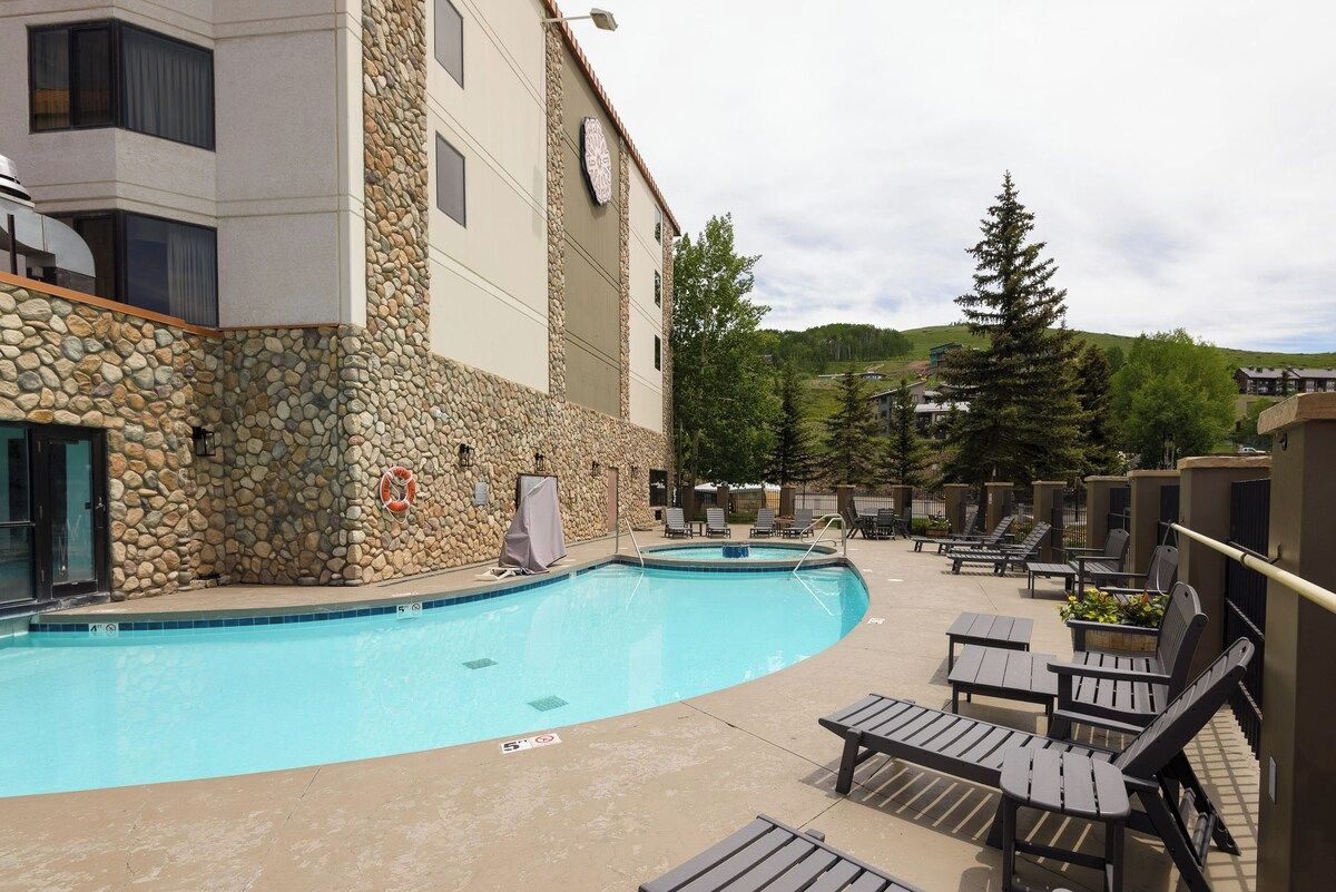 A pool area with lounge chairs and a stone wall.