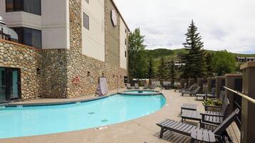 A pool area with lounge chairs and a stone wall.