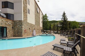 A pool area with lounge chairs and a stone wall. - NEW LISTING - 515 slope side 2 king view of Mt. Crested Butte (Crested Butte)
