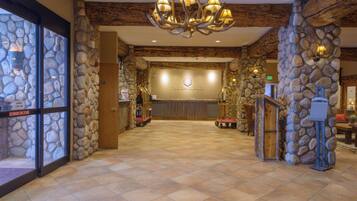 A reception area with a stone wall, a chandelier, and a sign that reads 'The Grand Lodge.'