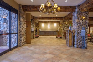 A reception area with a stone wall, a chandelier, and a sign that reads 'The Grand Lodge.' - NEW LISTING - 515 slope side 2 king view of Mt. Crested Butte (Crested Butte)