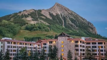 A hotel with multiple floors, a central tower, and a mountain backdrop.