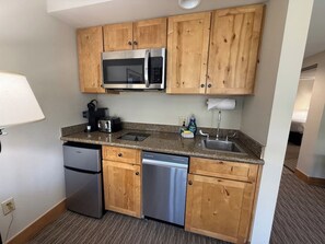 A compact kitchen with wooden cabinets, a stainless steel refrigerator, a dishwasher, a microwave, and a granite countertop. - NEW LISTING - 379-381 2-Bdrm Suite @ Base Area Mt. Crested Butte (Crested Butte)