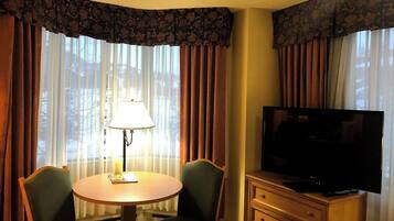 Een hotelkamer met een ronde tafel, twee stoelen, een televisie en een lamp.