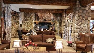 A cozy living room with a stone fireplace, leather furniture, and a rustic ceiling.