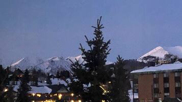 A hotel with a mountain backdrop, featuring a snow-covered peak and a building with illuminated windows.