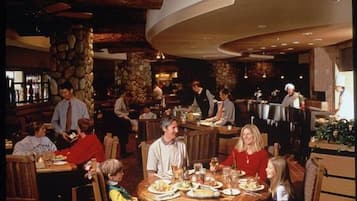 A restaurant with round tables, a stone wall, and a bar area.