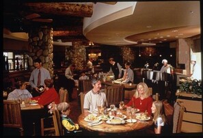 A restaurant with round tables, a stone wall, and a bar area. - NEW LISTING - 279 Slopeside King bed Studio Pet friendly! (Crested Butte)