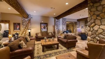 A spacious living room with leather sofas, a coffee table, and a stone accent wall.