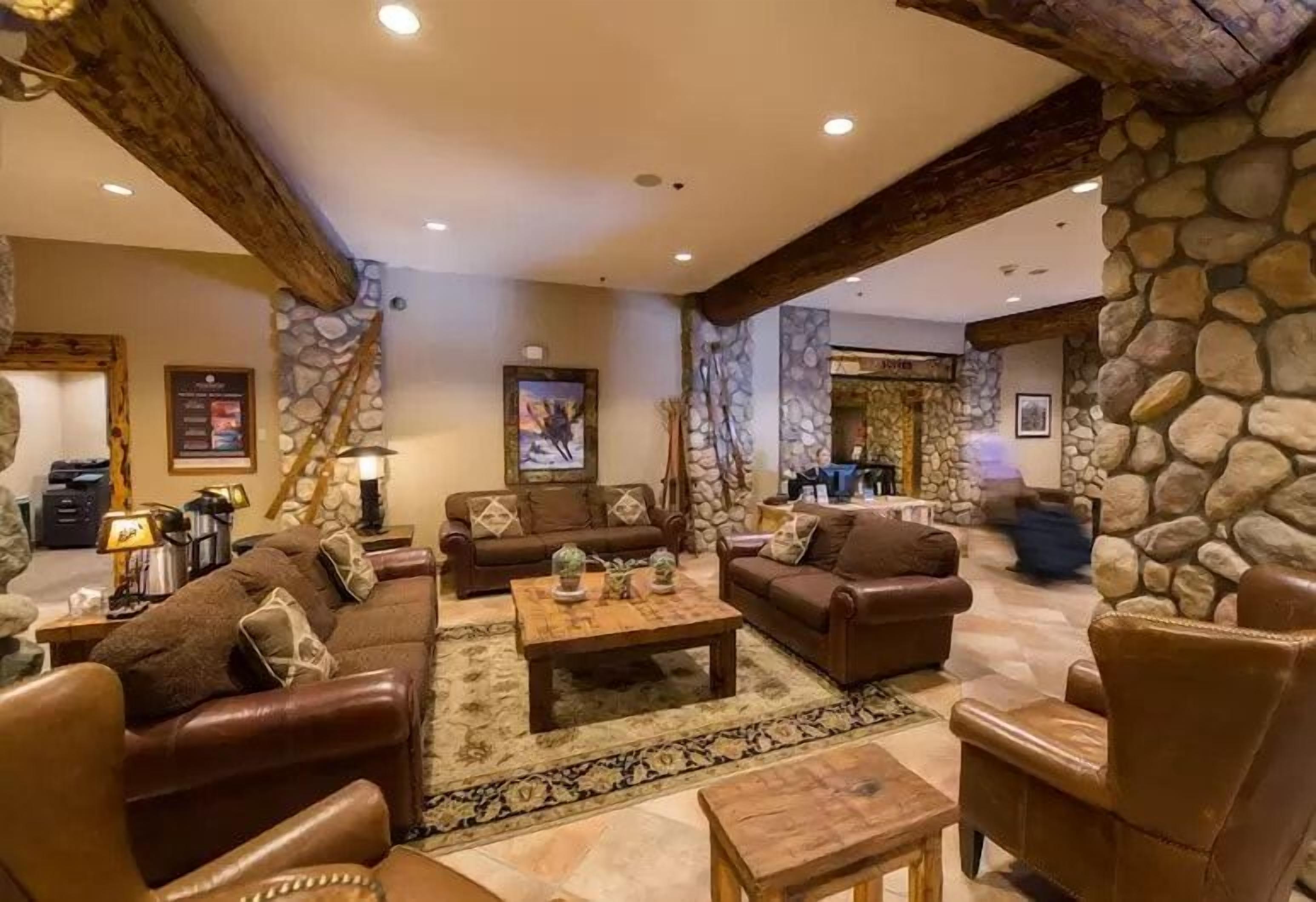 A spacious living room with leather sofas, a coffee table, and a stone accent wall.