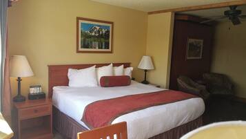 A hotel room with a bed, two bedside tables, a chair, and a painting on the wall.