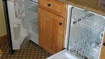 Una cocina compacta equipada con lavavajillas, cafetera y refrigerador pequeño.