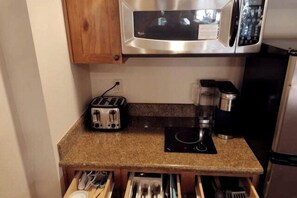 Une cuisine équipée d’un grille-pain, d’une machine à café et d’un four à micro-ondes.