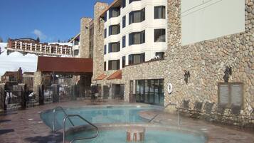 A hotel with a pool area, stone walls, and multiple balconies.