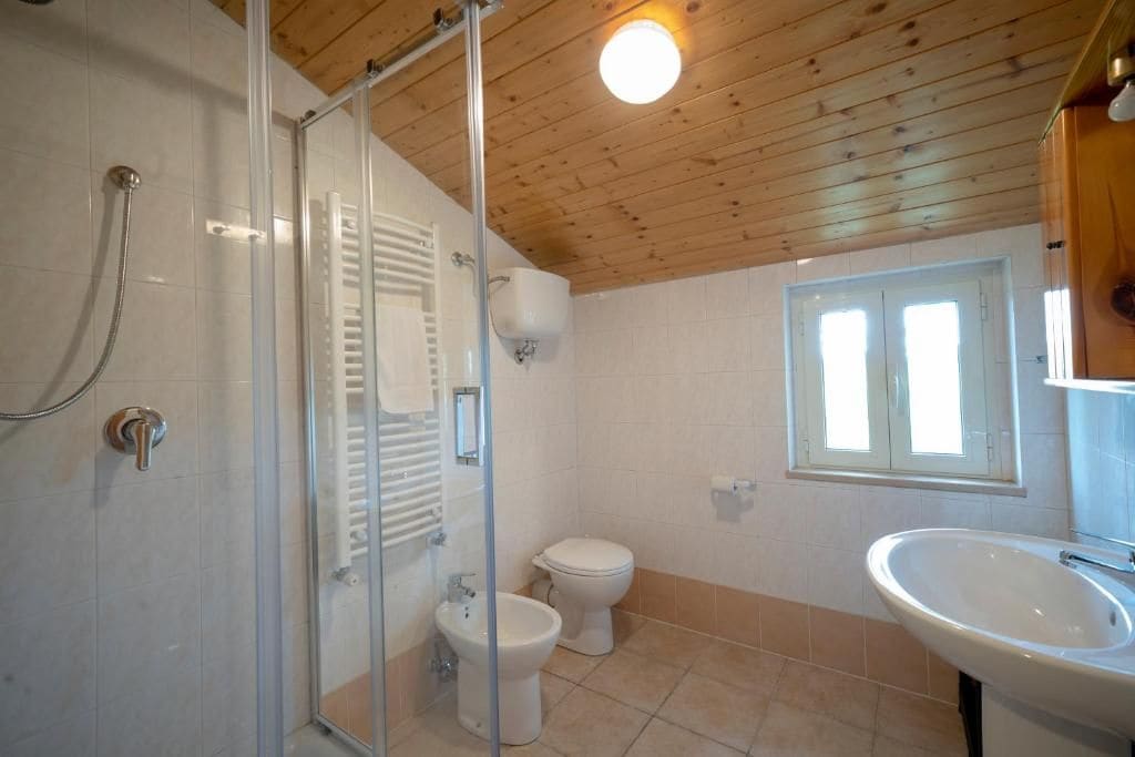 Un baño con cabina de ducha de vidrio, inodoro y lavabo.