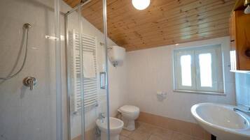 Un baño con cabina de ducha de vidrio, inodoro y lavabo.
