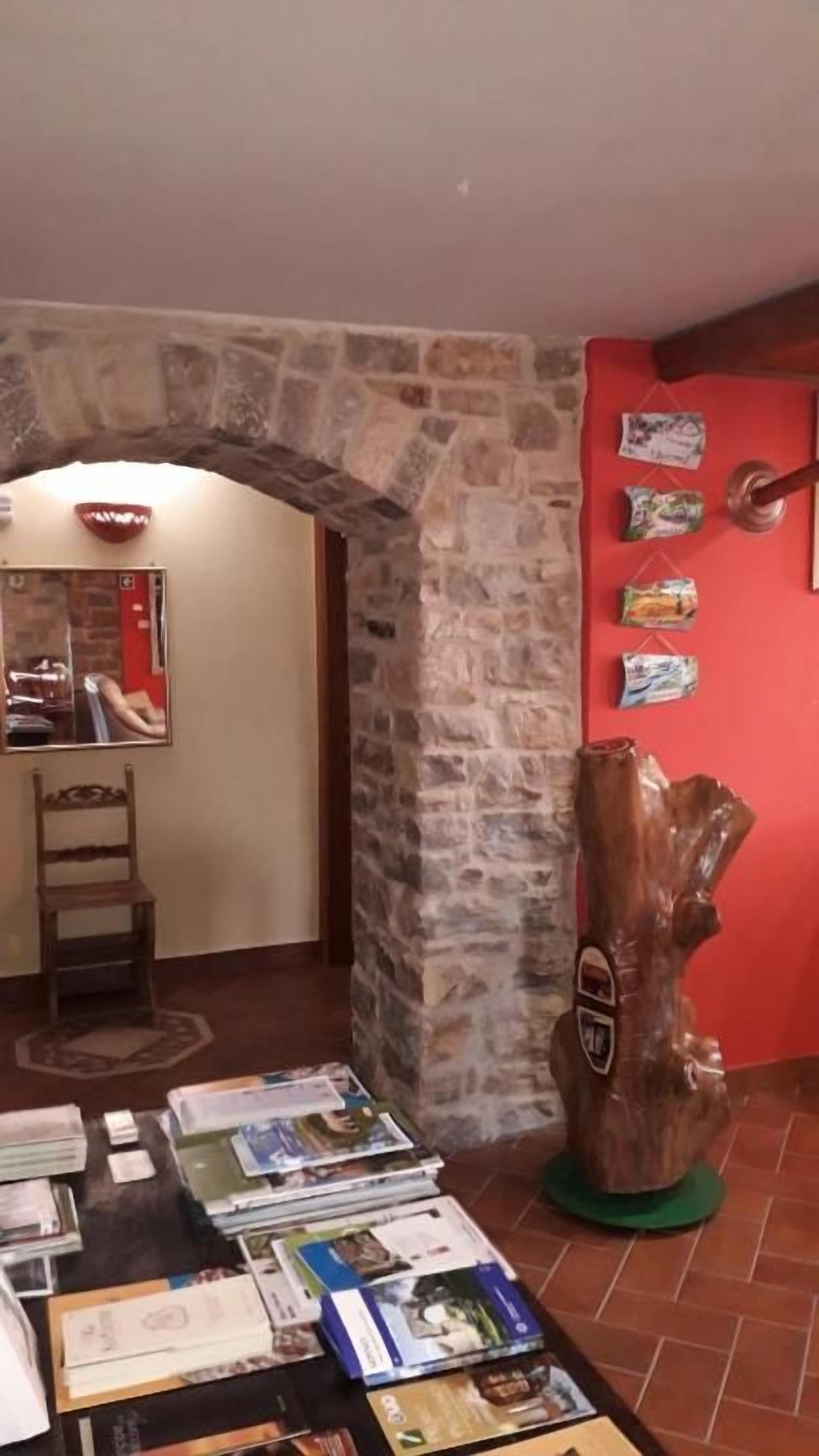 Una habitación con un arco de piedra, una escultura de madera y una mesa con revistas.