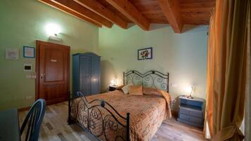 Un dormitorio con techo de madera, una cama con estructura metálica, una mesita de noche, un armario y una puerta.