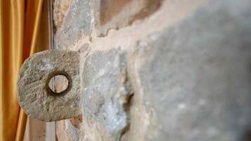 Primeiro plano de uma parede de pedra com um buraco circular, possivelmente uma janela ou abertura de porta.