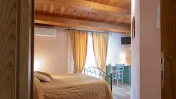 Ein Schlafzimmer mit Holzbalkendecke, einem Bett, einem Schreibtisch und Vorhängen.