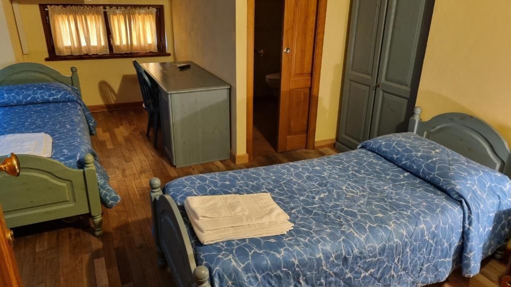 Una habitación con dos camas, un escritorio y un armario.