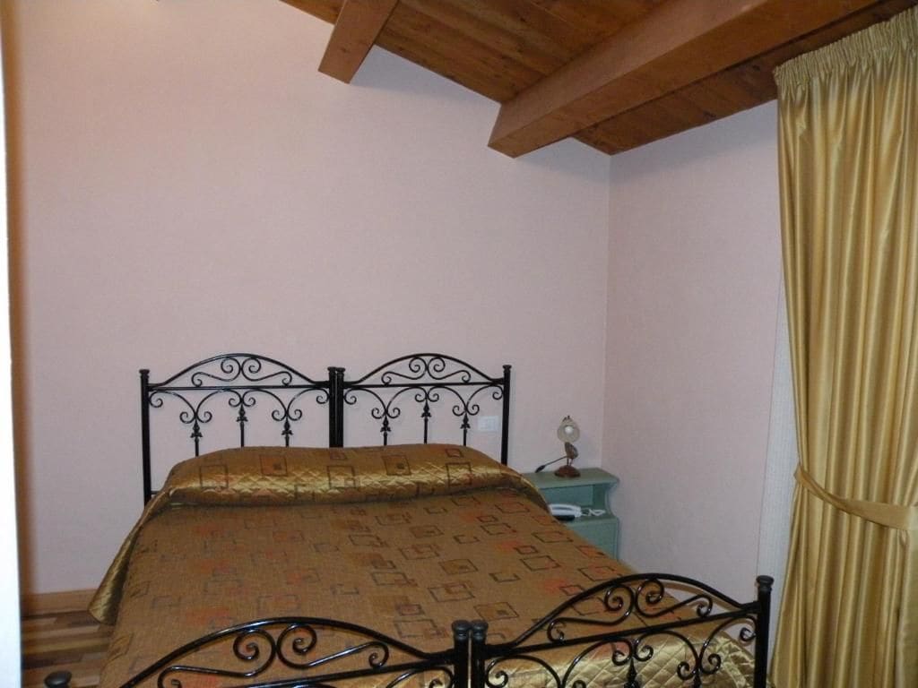 A room with a bed, a nightstand, and a curtain.