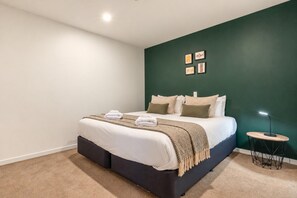 A bedroom with a bed, a bedside table, a lamp, and artwork on the wall. - Central Courtyard - Free parking · 250 m to town (Queenstown)