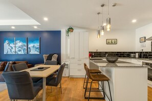A modern kitchen with a central island, white cabinetry, and a black backsplash. - Central Courtyard - Free parking · 250 m to town (Queenstown)