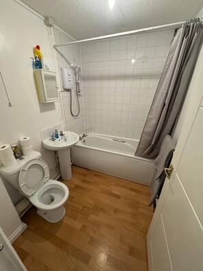A compact bathroom with a toilet, sink, and bathtub. - Charming 1-bedroom Apartment in West Northamptonshire (Northampton)