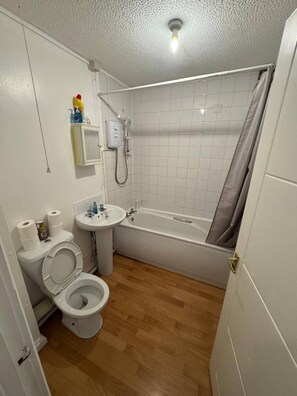 A bathroom with a toilet, sink, and bathtub. - Charming 1-bedroom Apartment in West Northamptonshire (Northampton)