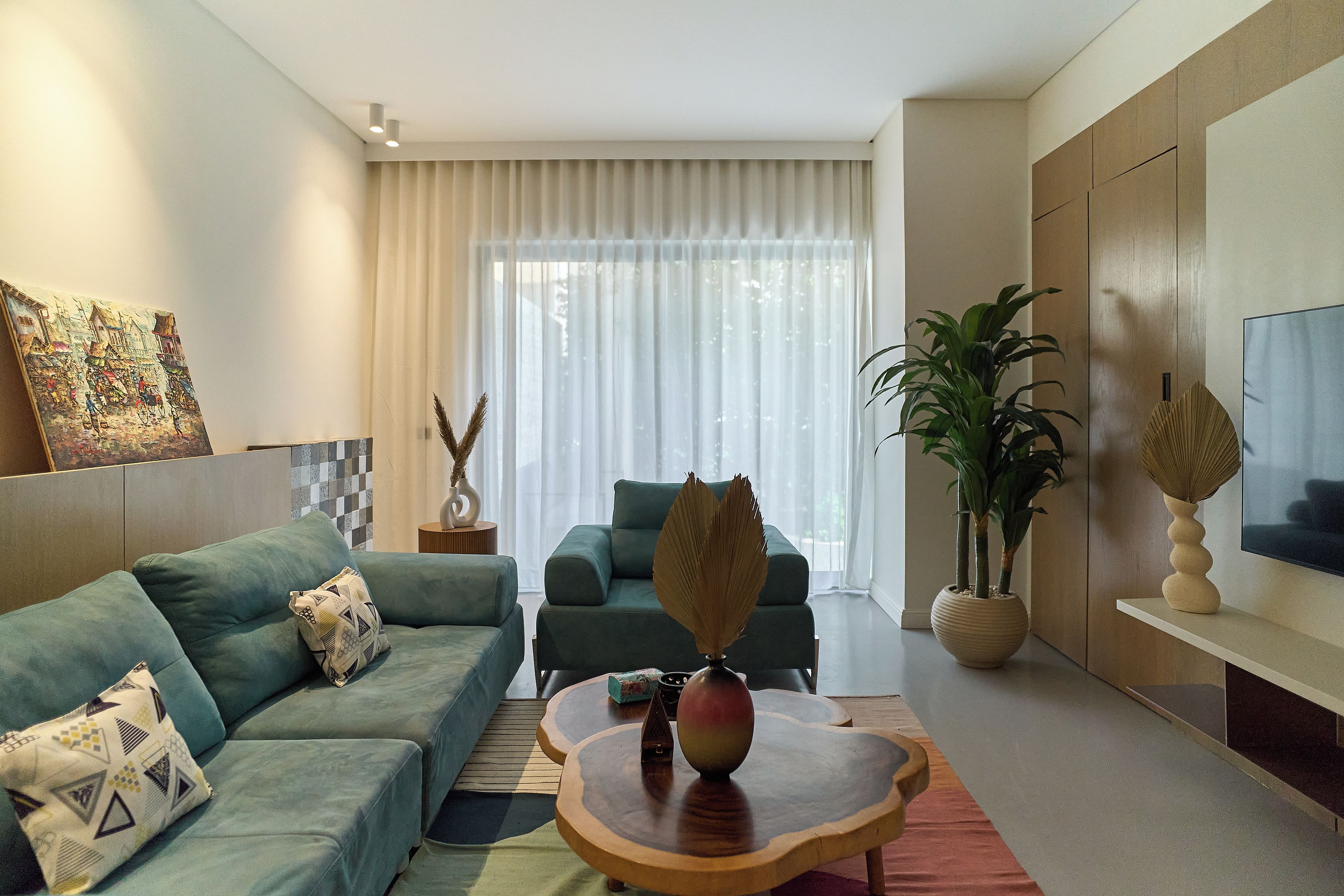 Un salon moderne comprenant un canapé, un fauteuil, une table basse et un téléviseur.