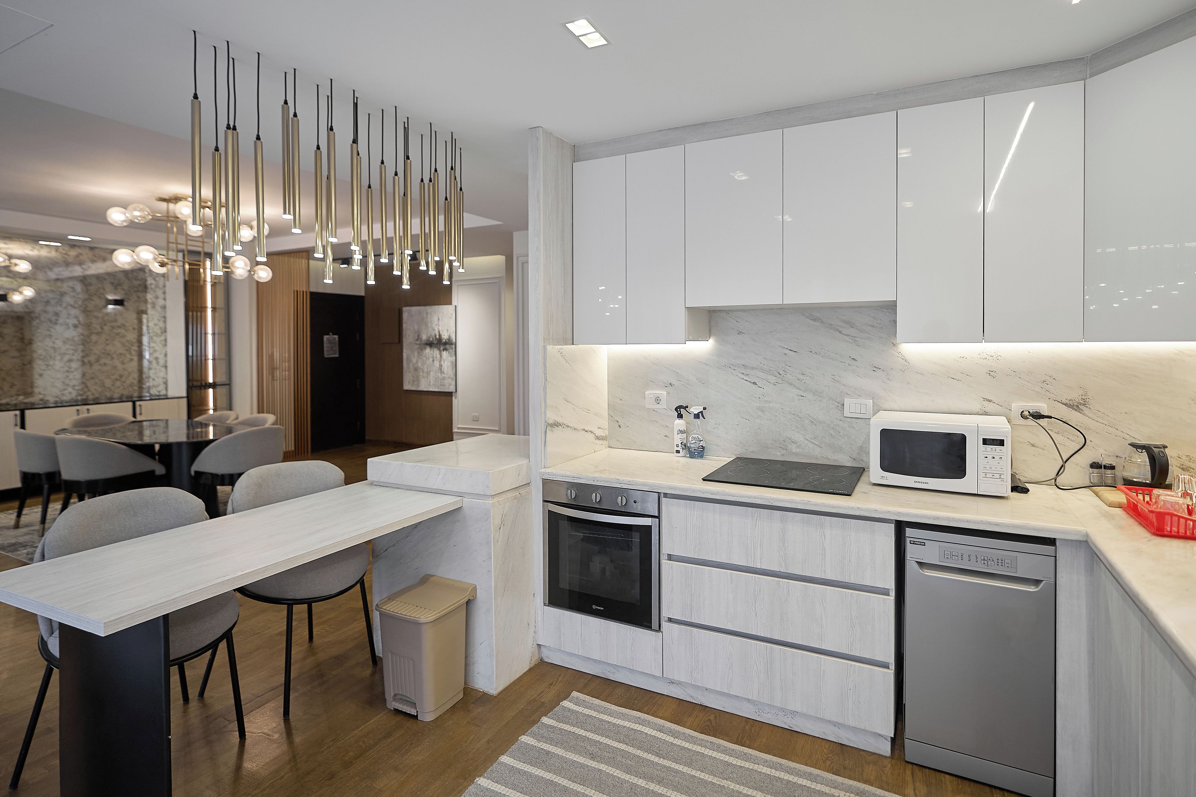A modern kitchen with white cabinetry, a built-in oven, a microwave, and a dishwasher.