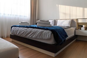 Una habitación de hotel moderna con una cama grande, una mesita de noche y un pupitre.