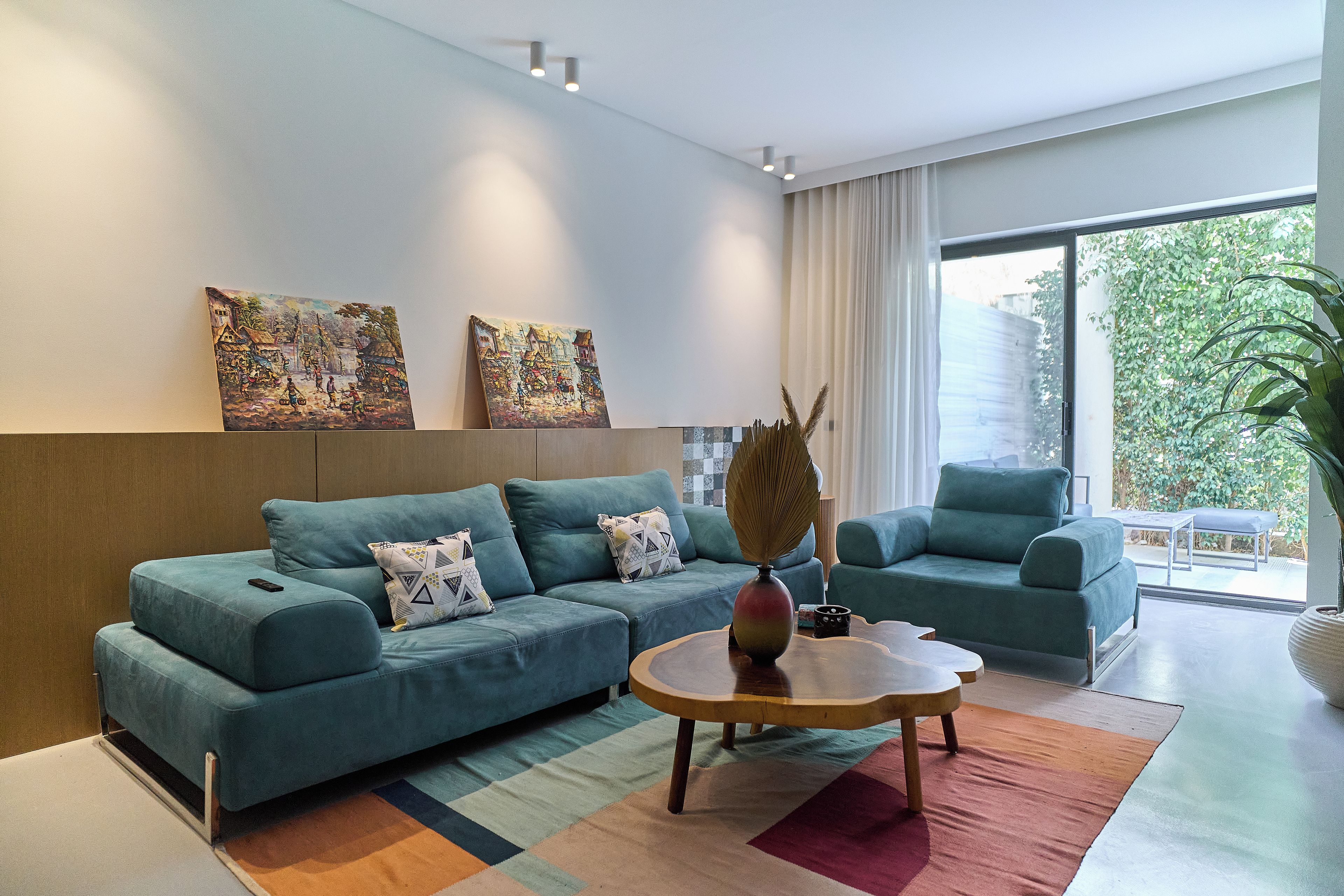 Una sala moderna con sofá, sillón, mesa de centro y una obra de arte en la pared.
