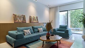 Una sala moderna con sofá, sillón, mesa de centro y una obra de arte en la pared.